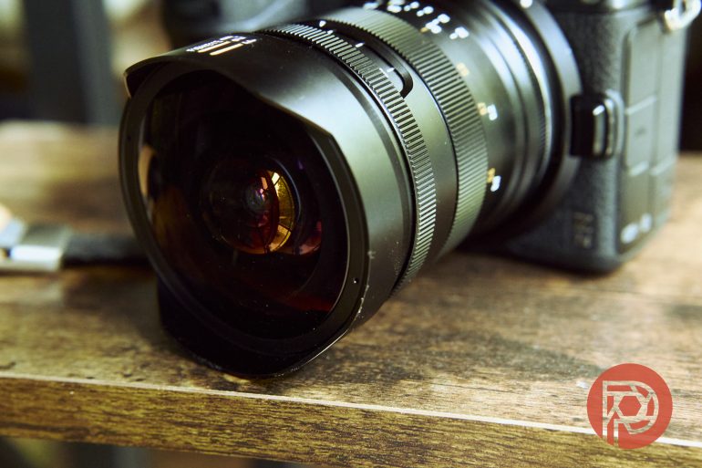 Close-up of a DSLR camera with a wide-angle lens resting on a wooden surface.