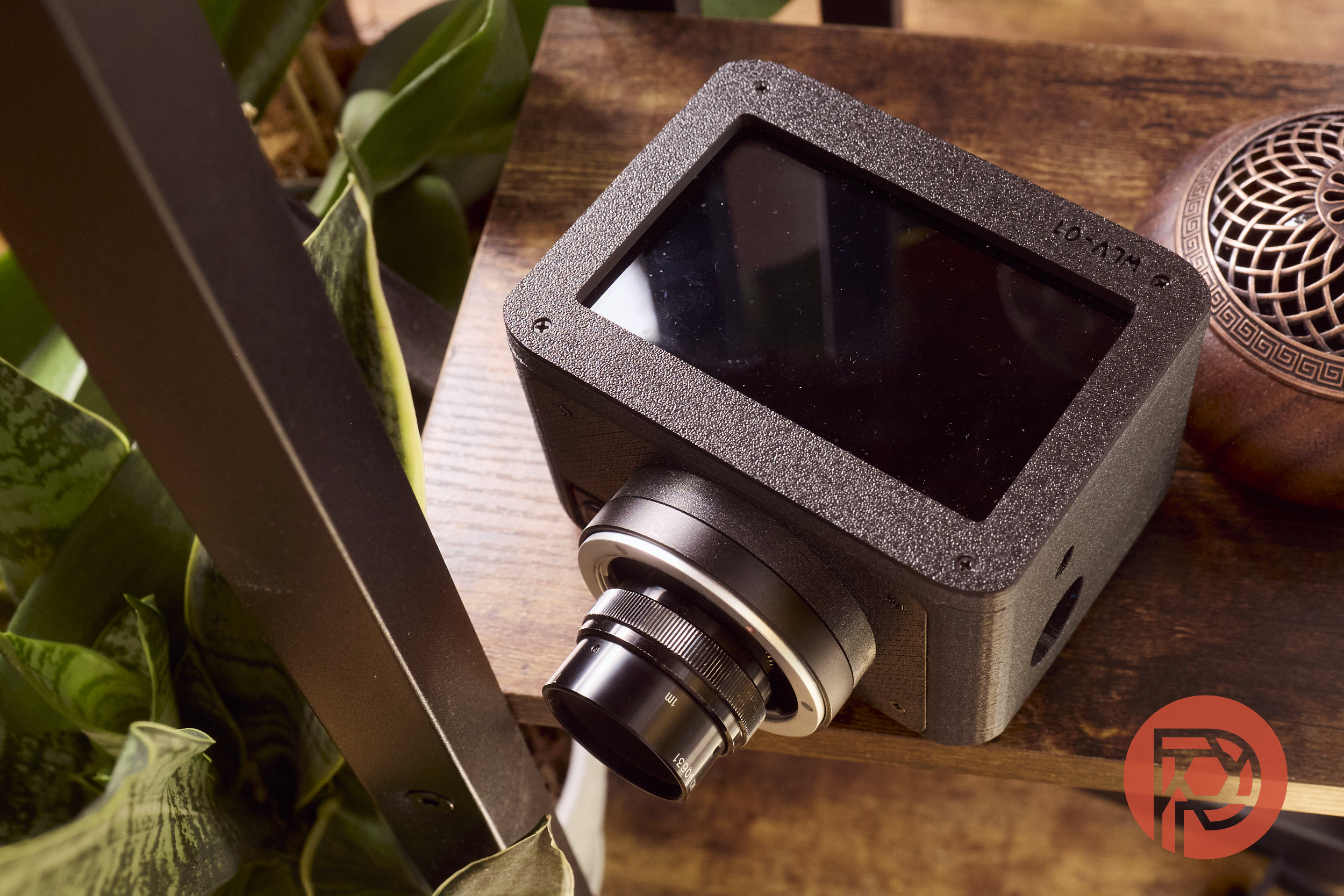 The Monochrome WLV-01 Waist Level Camera Review: The Sony E Mount Just Got Better A black box-style camera with a large lens on a wooden table, surrounded by plants and wooden decor.