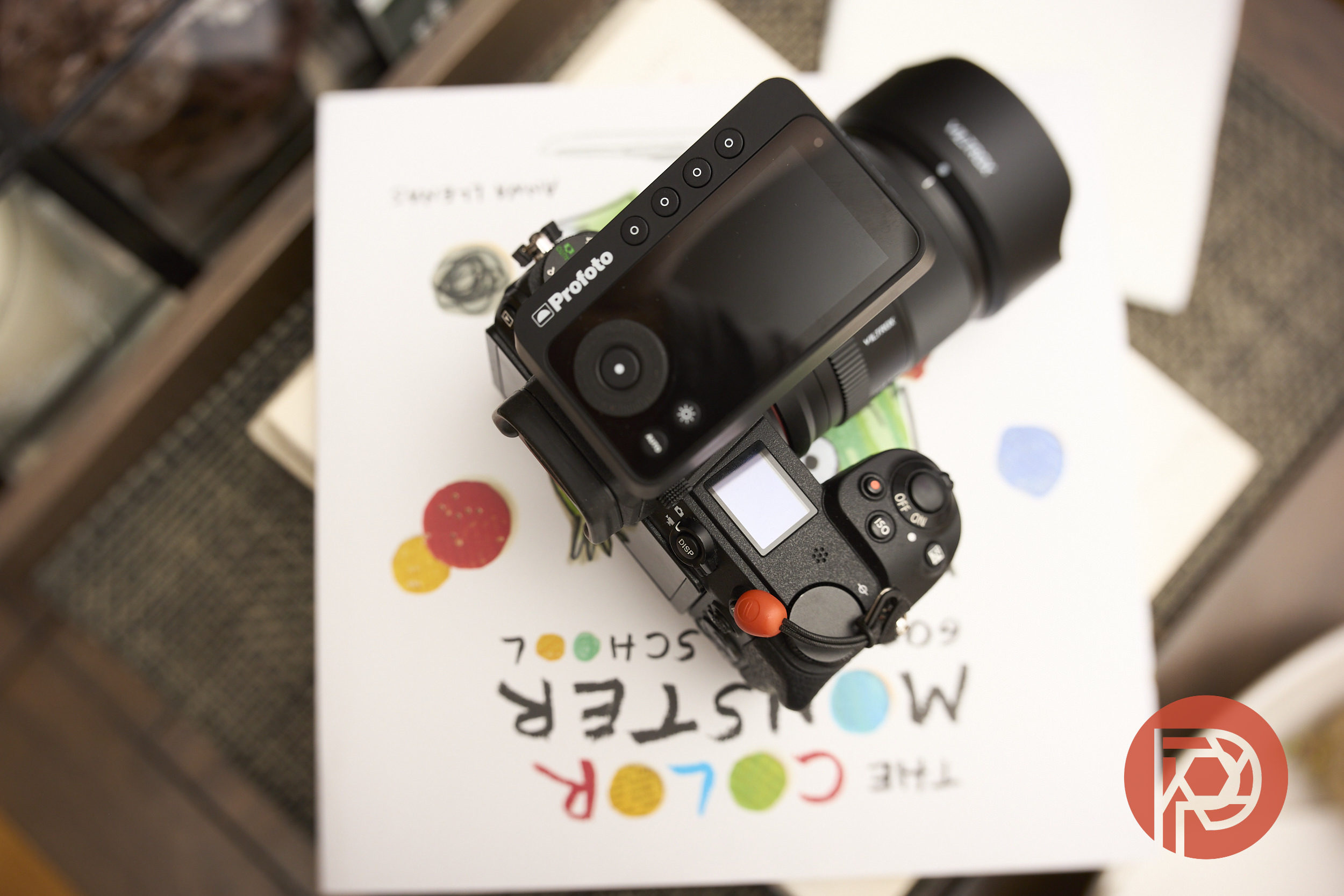 A camera with a Profoto trigger sits on a colorful book cover titled The Color Monster.