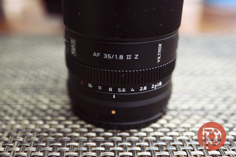 Close-up of a Viltrox AF 35/1.8 II Z camera lens on a textured, woven surface.