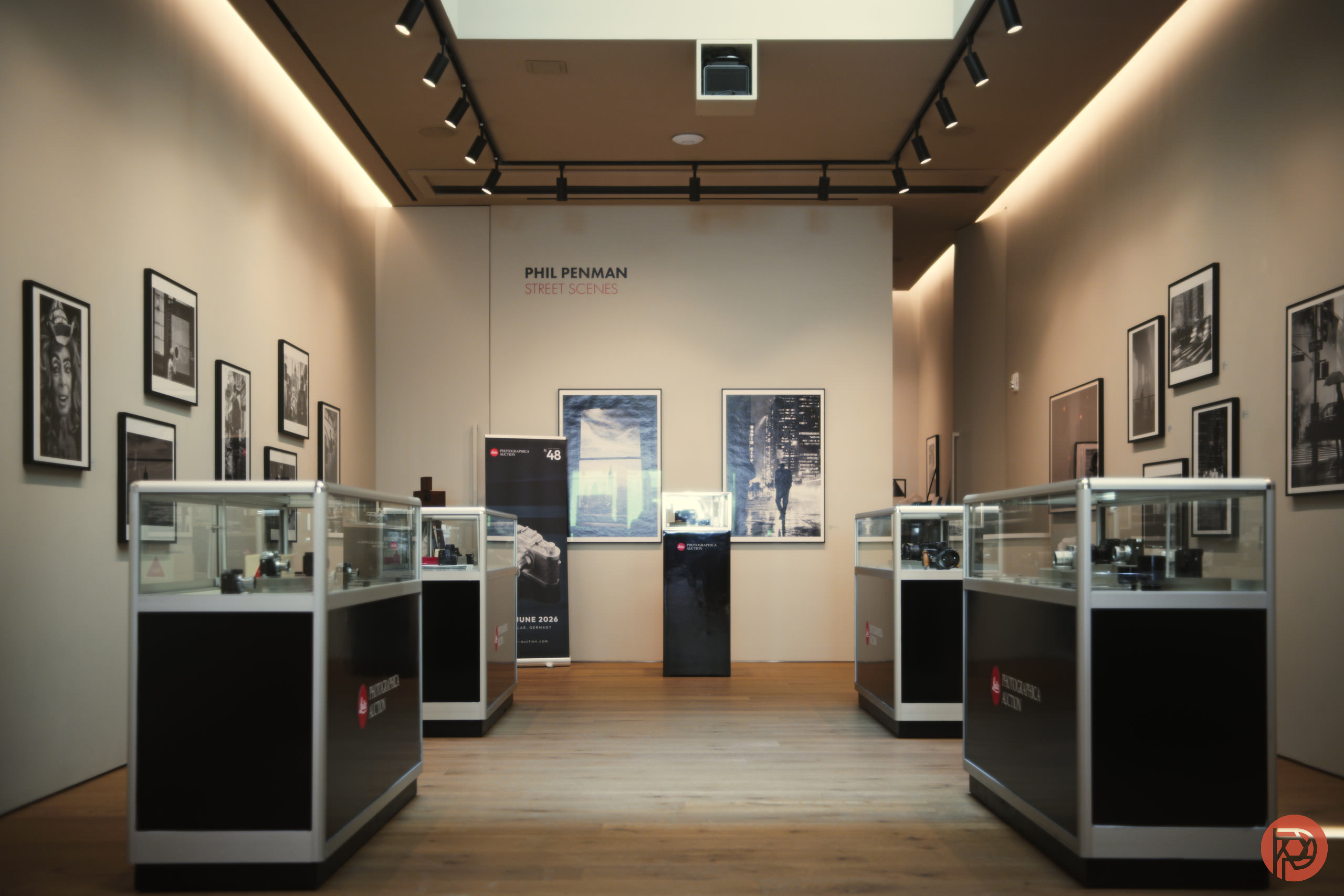 A modern gallery with glass display cases, framed photos on the walls, and wooden floors.