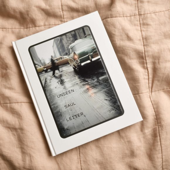 A book titled The Unseen Saul Leiter rests on a beige quilted blanket.