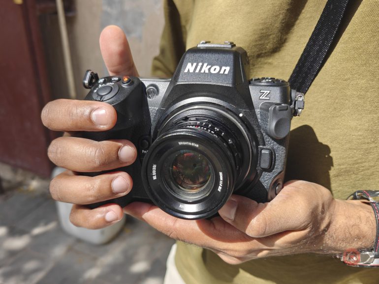 A person holding a Nikon Z camera with both hands, wearing a green shirt.