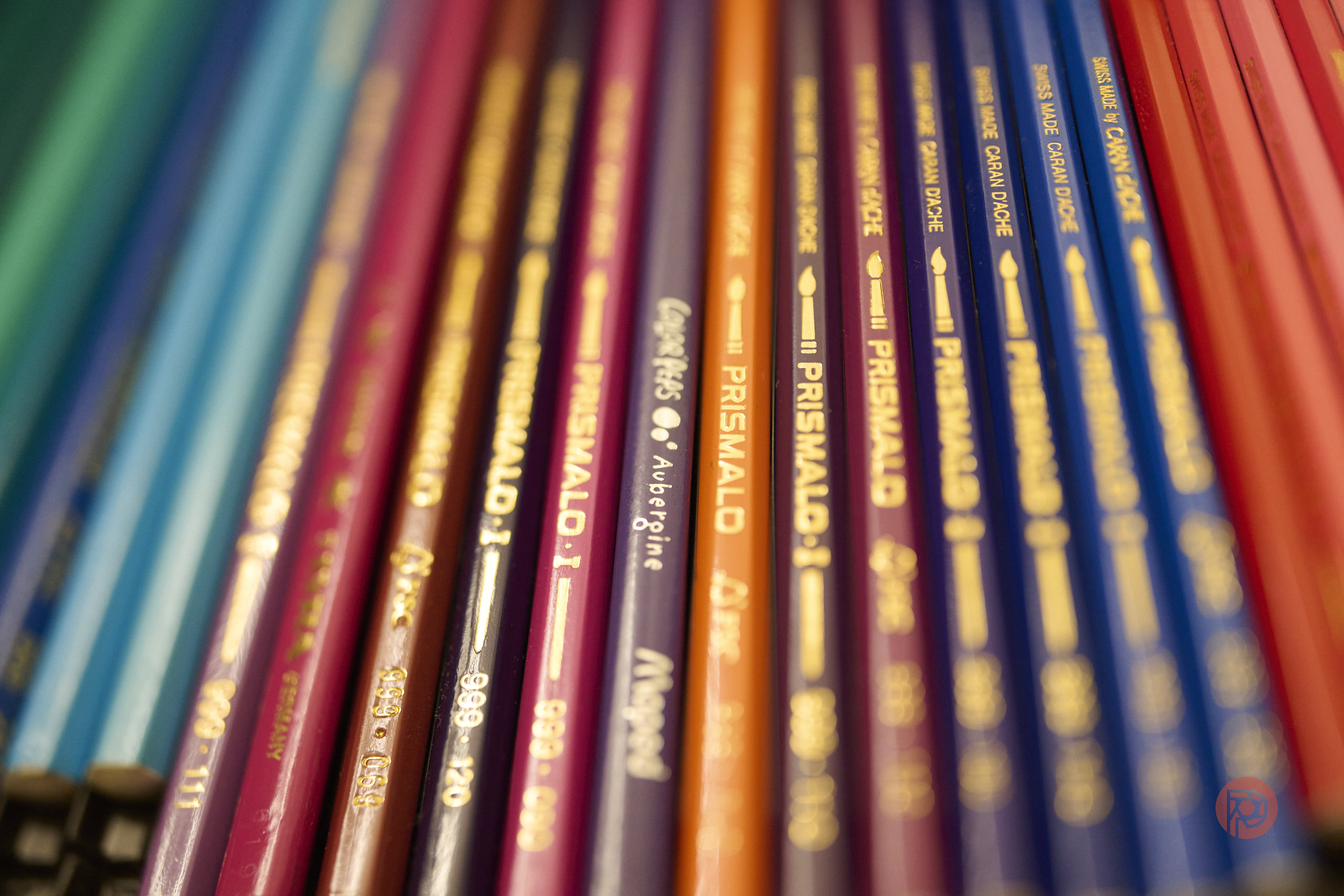 Close-up of colorful Prismacolor pencils arranged in parallel rows, showing brand names and color labels.