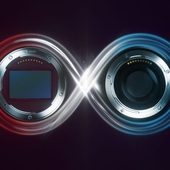 Two camera lens mounts connected by a glowing infinity symbol with red and blue light accents.