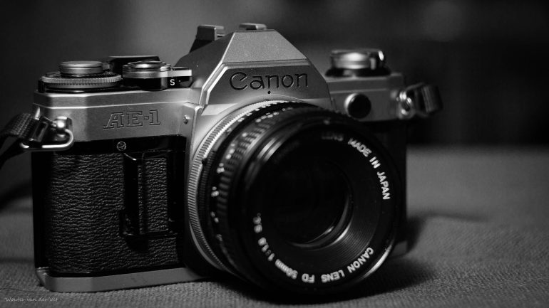 Black and white close-up of a Canon AE-1 film camera with a Canon FD lens attached.