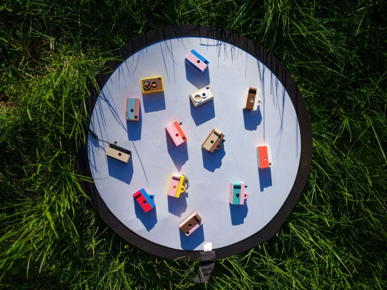 Colorful toy blocks arranged on a round white mat, placed on green grass under sunlight.