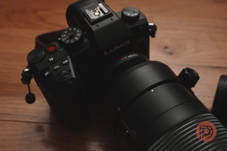 Close-up of a black Lumix camera with a large lens on a wooden surface.