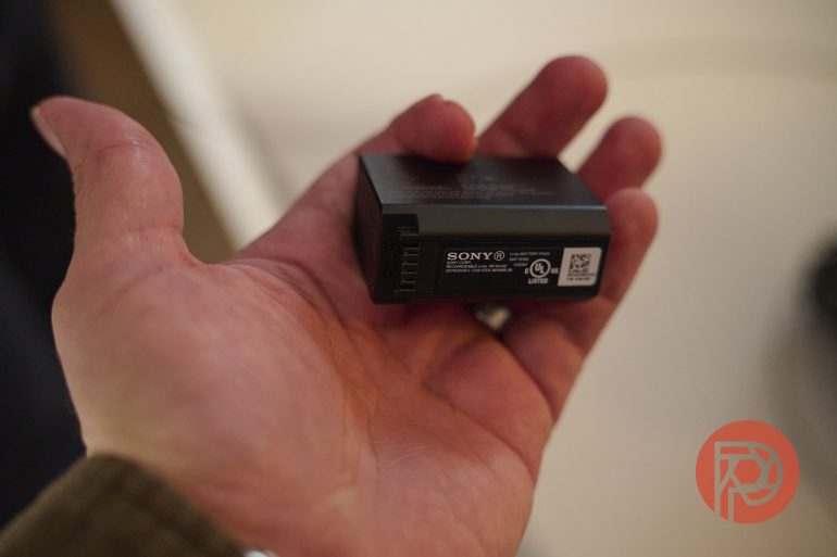 A hand holding a Sony rechargeable camera battery with a visible label.