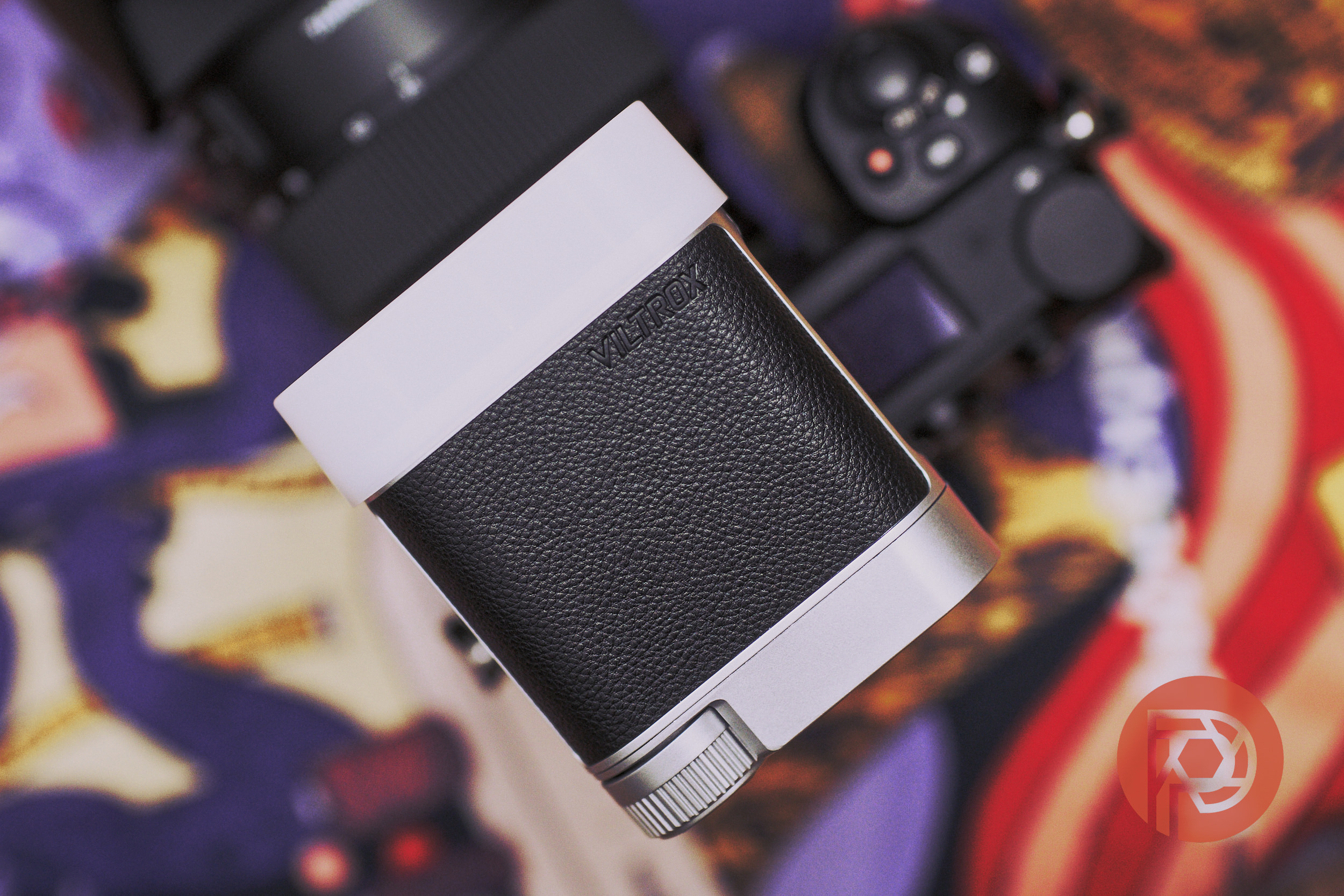 Viltrox Vintage Z1 Pro Review: An Affordable Pocket Flash with TTL and High-Speed Sync Close-up of a camera with a textured grip and lens, placed on a colorful, blurred background.