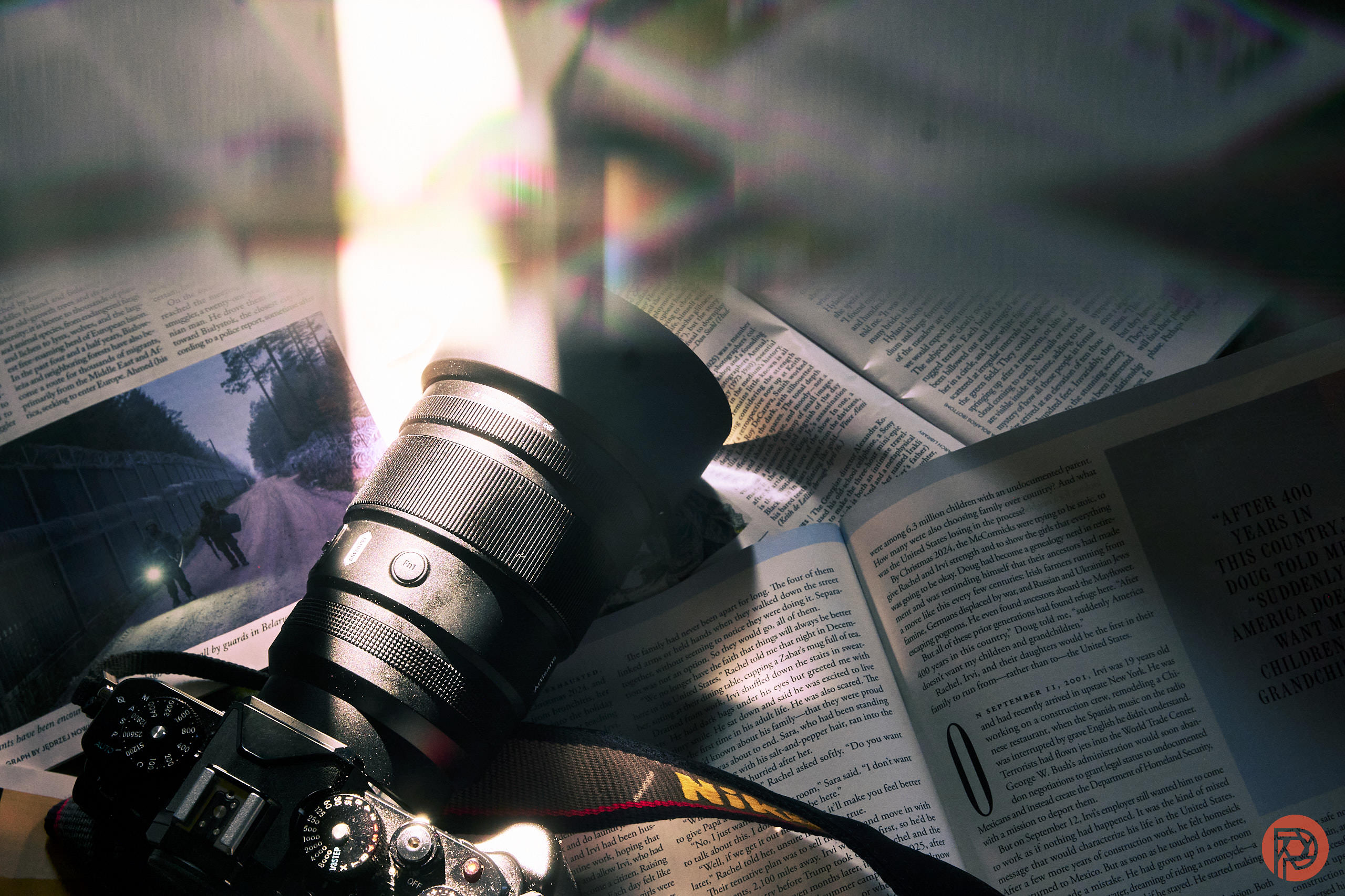 Is Sigma Quietly Building More Lenses for Portrait Photographers? A DSLR camera with a lens sits on open magazines, with light flares and reflections above it.