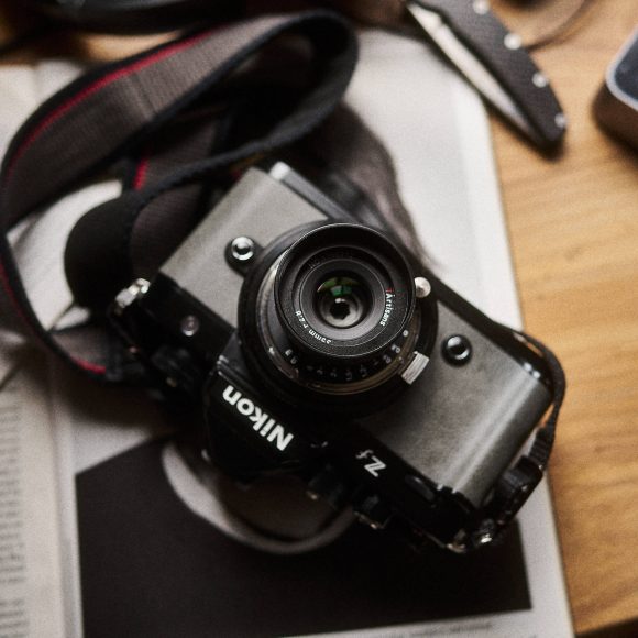 A Nikon Z fc camera with a 7Artisans 35mm f/2.8 lens is resting on a newspaper.