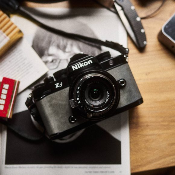 Nikon Zf camera with cigarettes, pocket knife, and phone on a wooden table.