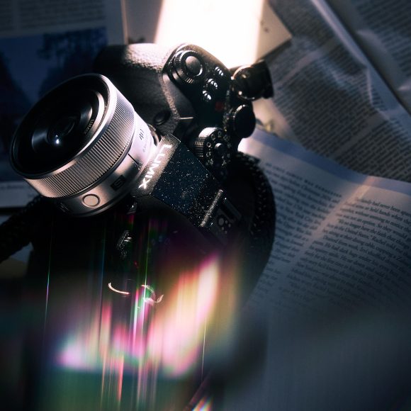 A Fujifilm camera resting on open books, illuminated by dramatic, colorful lighting effects.
