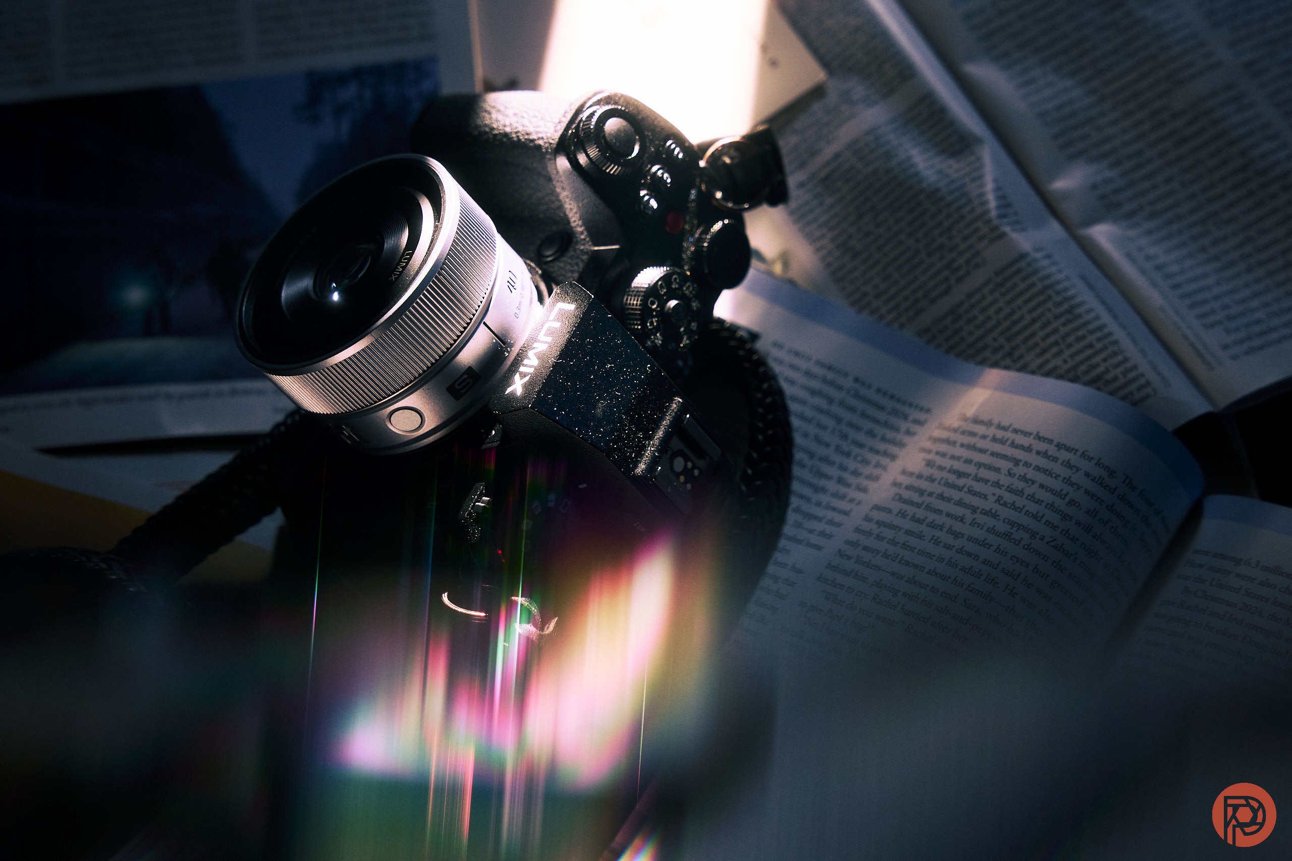 LUMIX 40mm f2 Review: What We Always Wanted A Fujifilm camera resting on open books, illuminated by dramatic, colorful lighting effects.