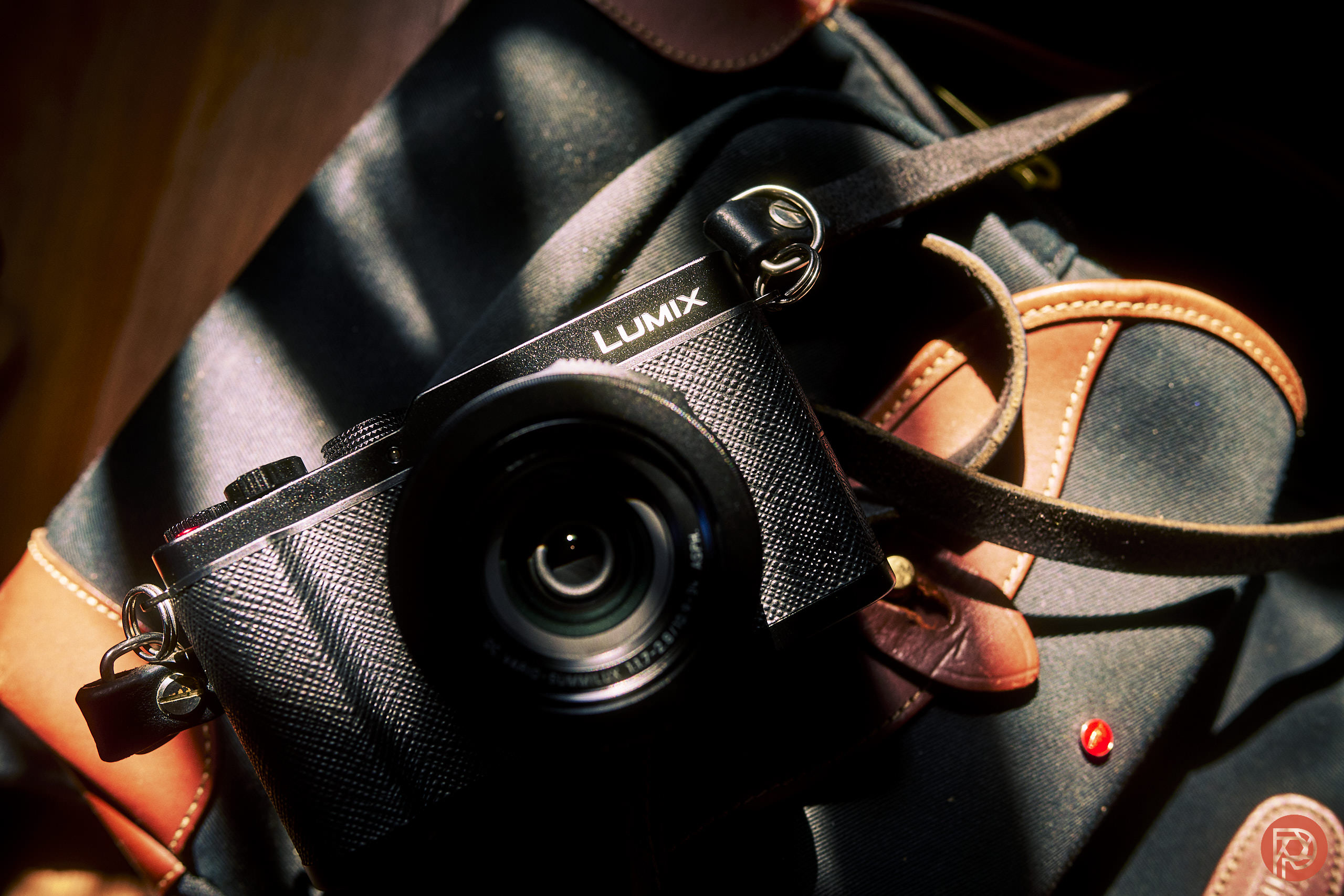 LUMIX L10 Review: A Photographer's Favorite Camera? A Lumix camera rests on a dark bag with brown leather accents, lit by a beam of sunlight.