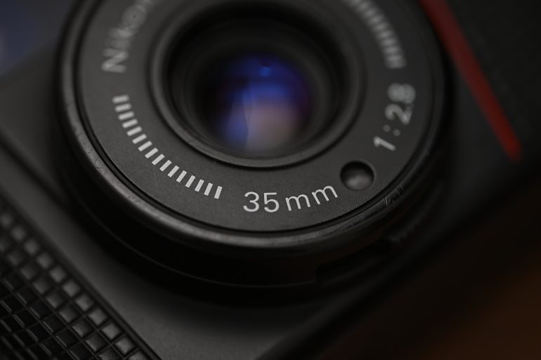 Close-up of a camera lens showing 35mm and aperture marking 1:2.8 on the lens ring.