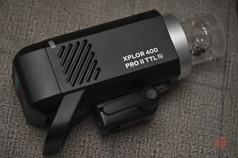 A Godox XPLOR 400 Pro II TTL camera flash resting on a textured surface.