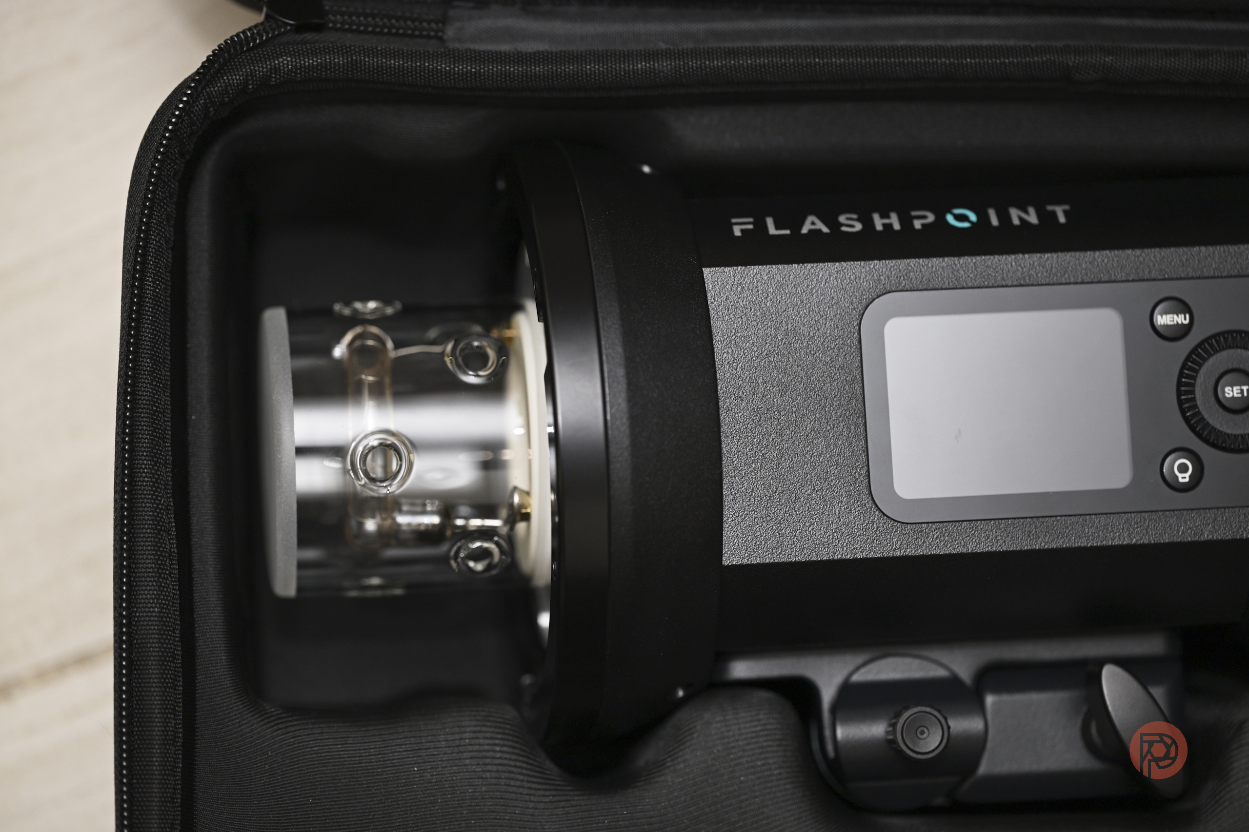 A Flashpoint studio strobe light with a digital display, packed inside a protective case.