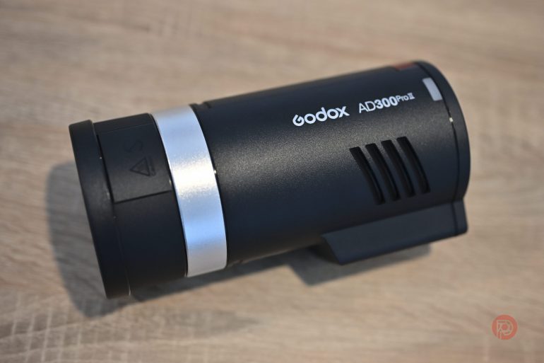 Godox AD300Pro flash unit placed on a wooden surface, viewed from a slight angle.