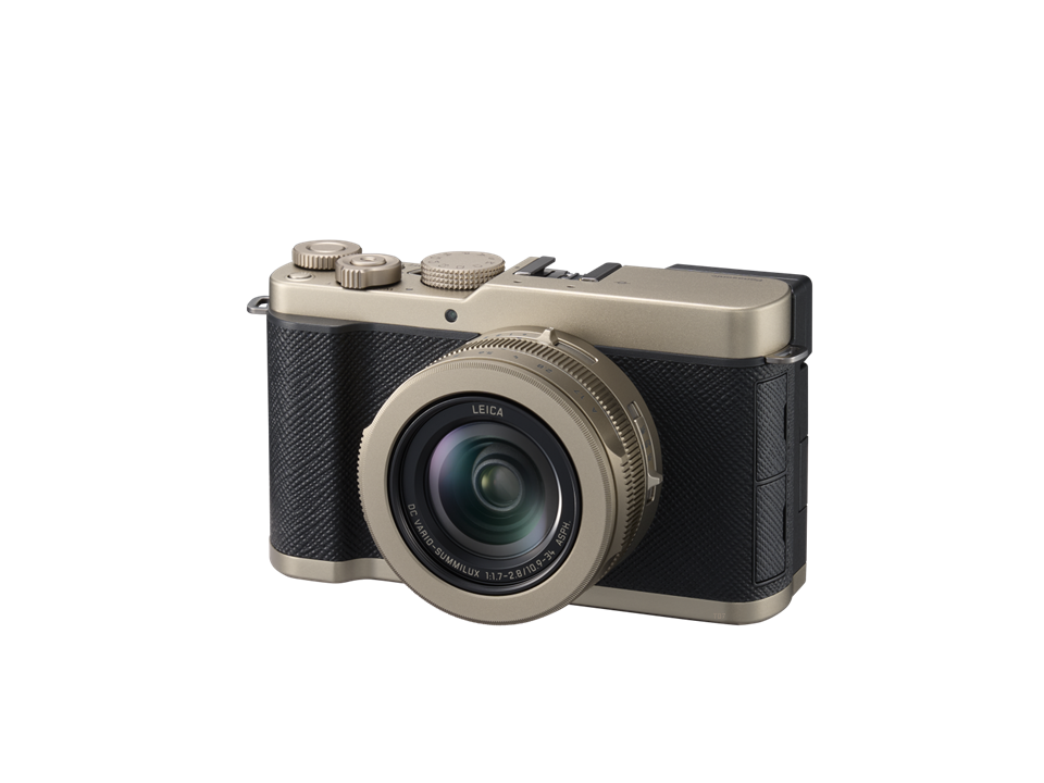 A compact digital camera with a wide lens, black grip, and metallic gold accents, viewed from the front left side.