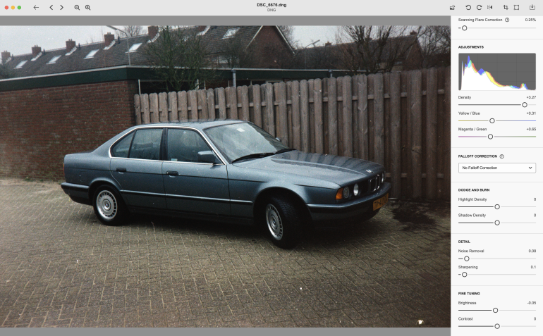 A blue sedan parked on a brick driveway in front of a wooden fence, with image editing tools visible.