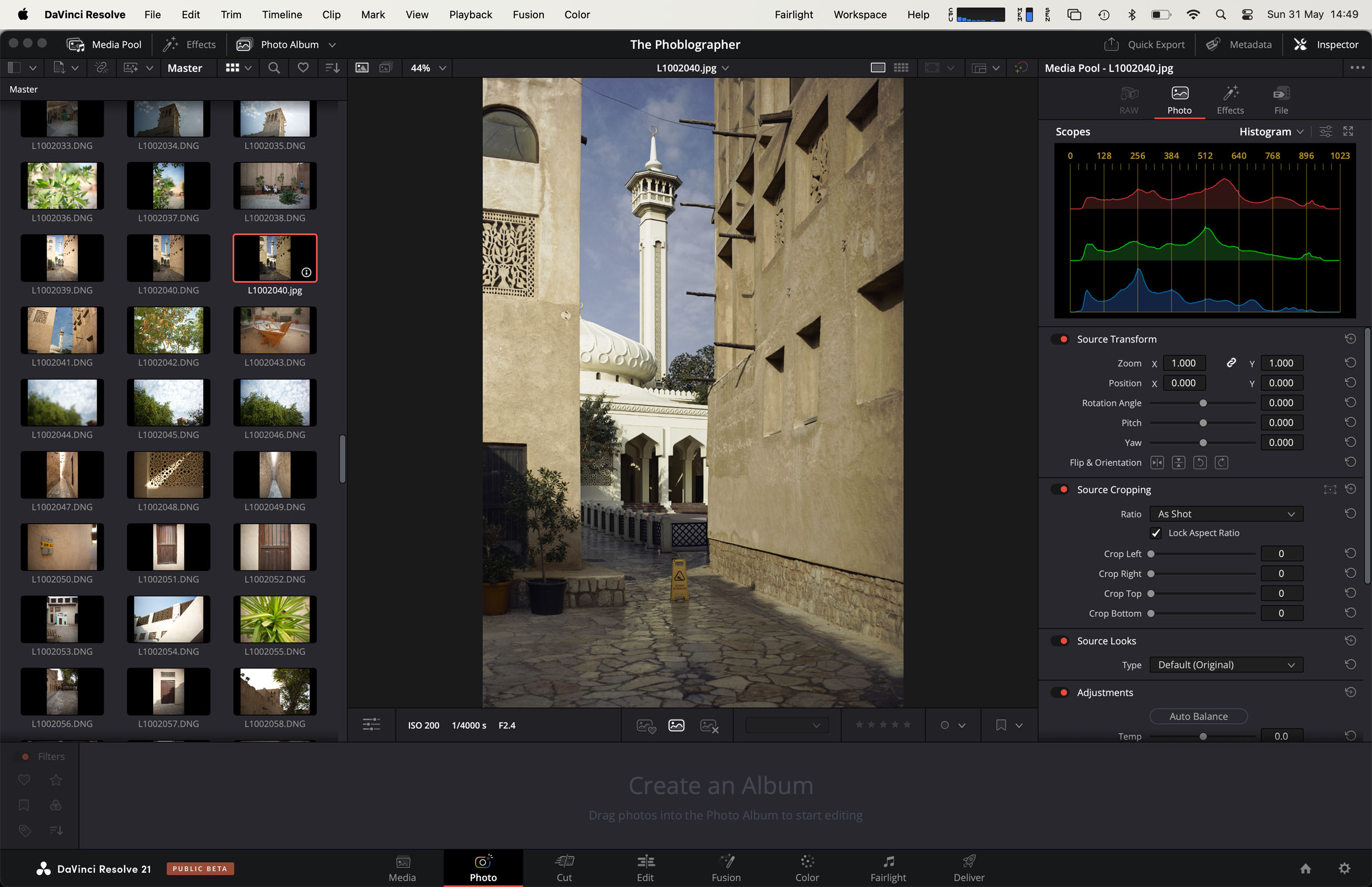 Editing software showing a photo of a narrow alley with a tower and mosque in daylight on the main screen.