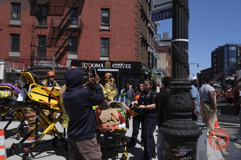 Firefighters and paramedics assist at an emergency scene on a city street with people and stretchers visible.