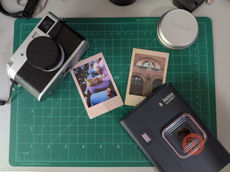 Two instant cameras, film, and two instant photos on a green cutting mat.