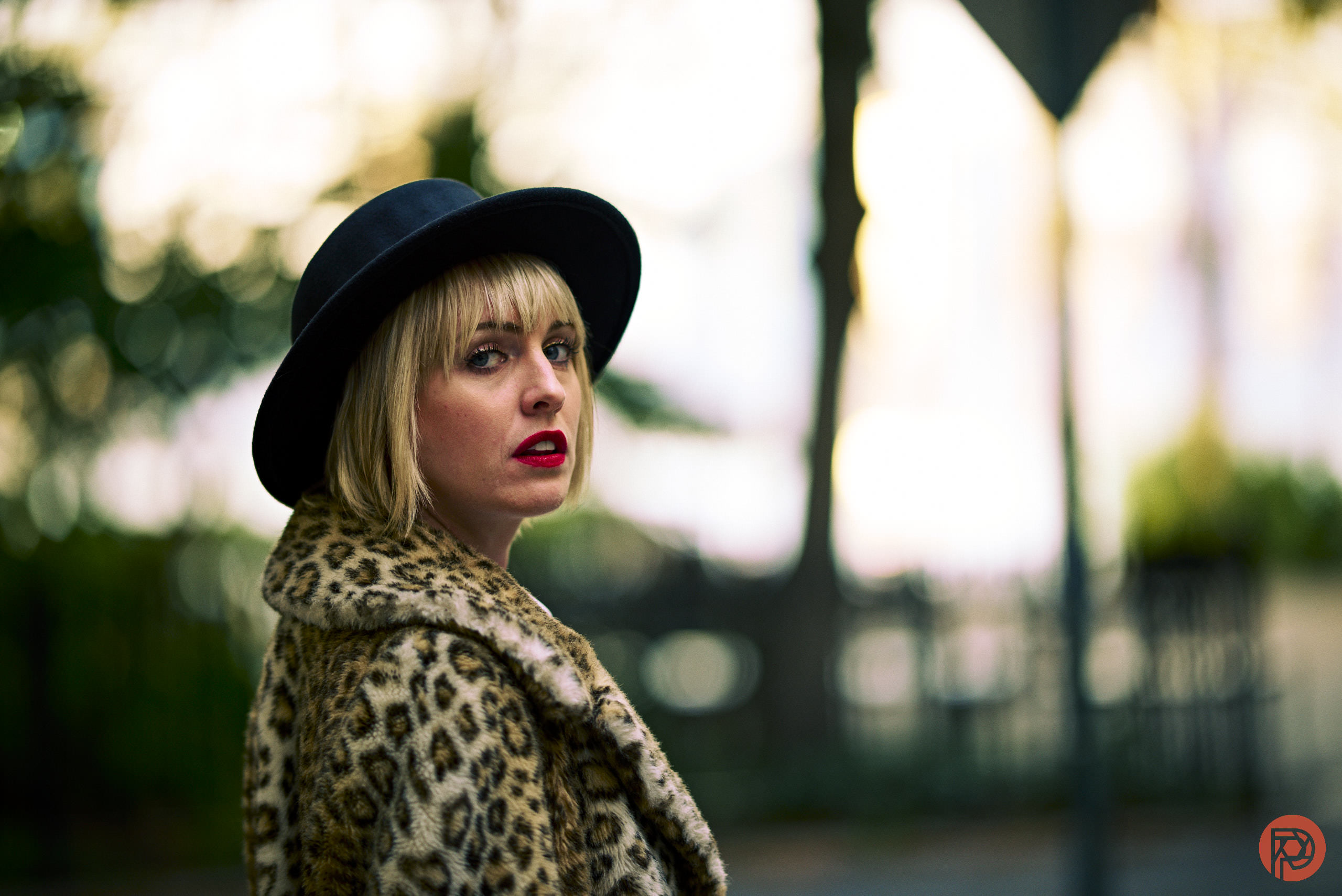 The Best Lens Nikon Made in the Past 10 Years Woman in a leopard print coat and black hat standing outdoors, looking over her shoulder.
