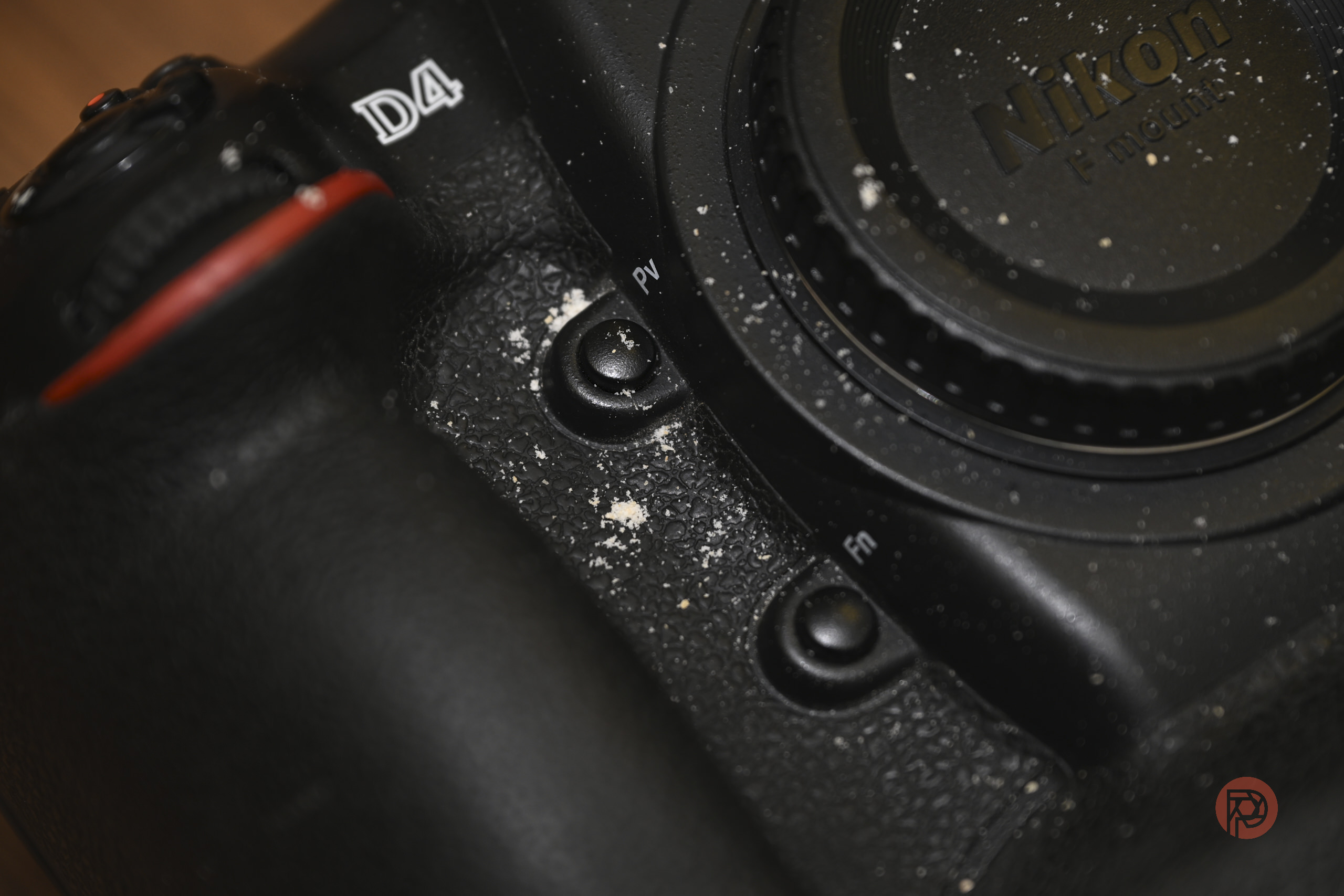 Close-up of a dusty Nikon D4 camera with visible dirt near the buttons and lens mount.