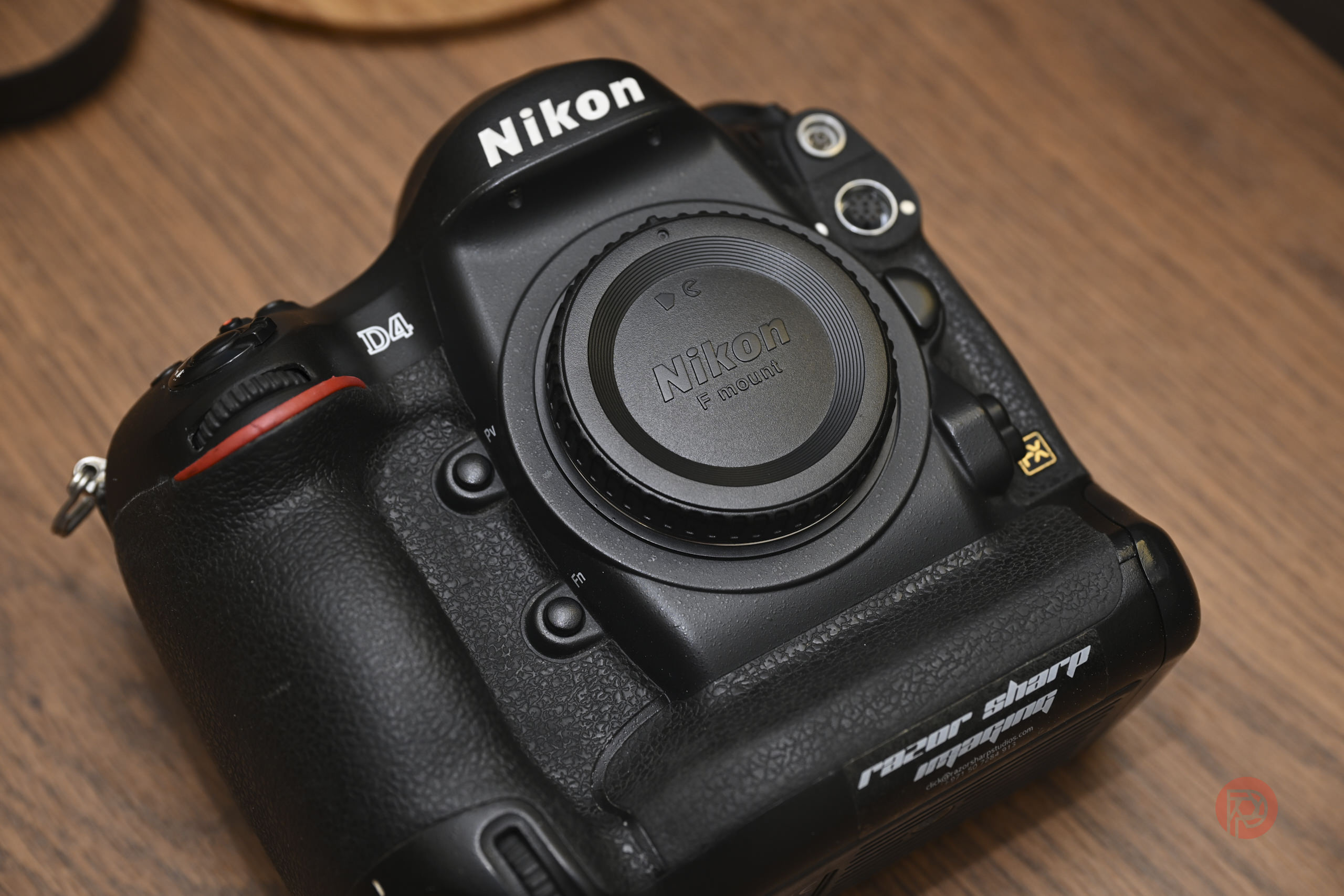 A Nikon D4 DSLR camera body with a body cap, resting on a wooden surface.