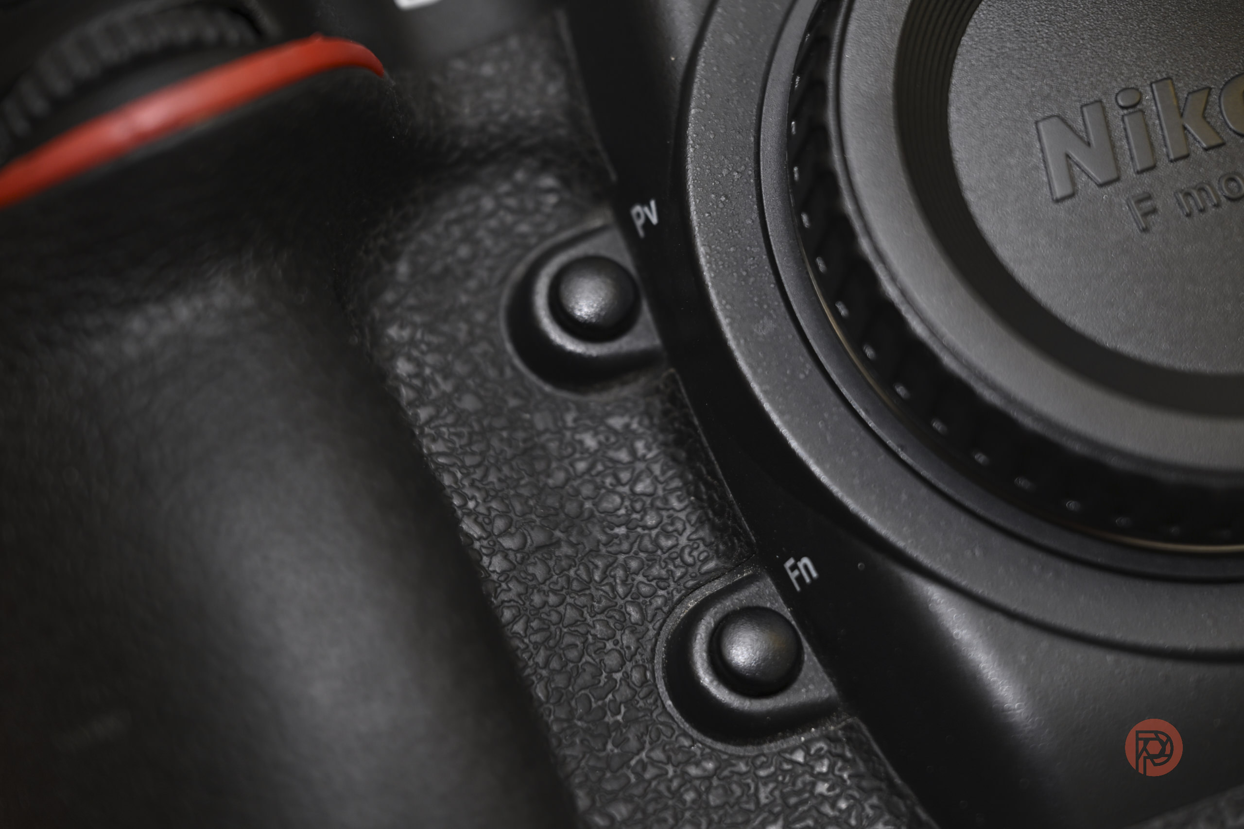 Close-up of a Nikon camera body showing grip texture, control buttons, and part of the lens mount.