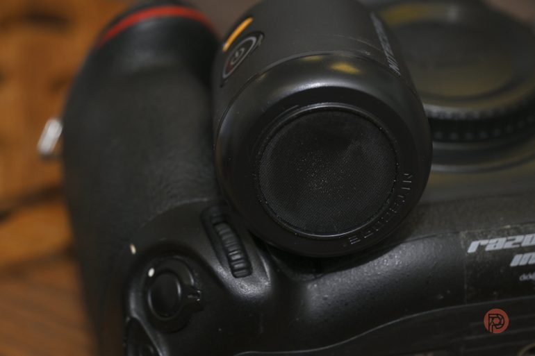 A small shotgun microphone is mounted on top of a black DSLR camera.