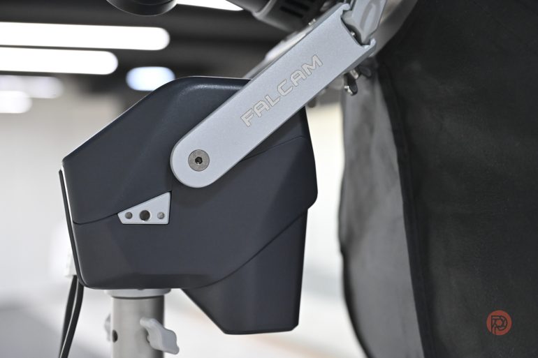 Close-up of a FALCAM branded camera accessory mounted on a stand in an indoor setting.