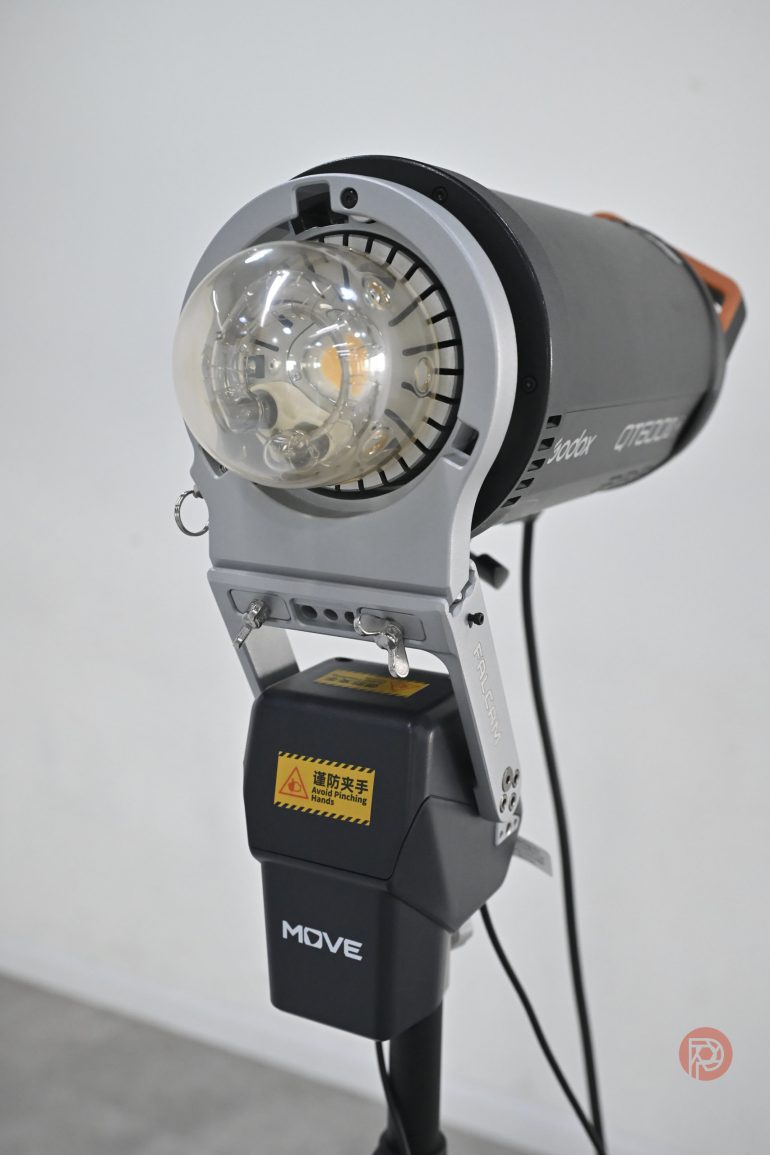 A studio strobe light with a visible bulb and attached power pack labeled MOVE on a stand.