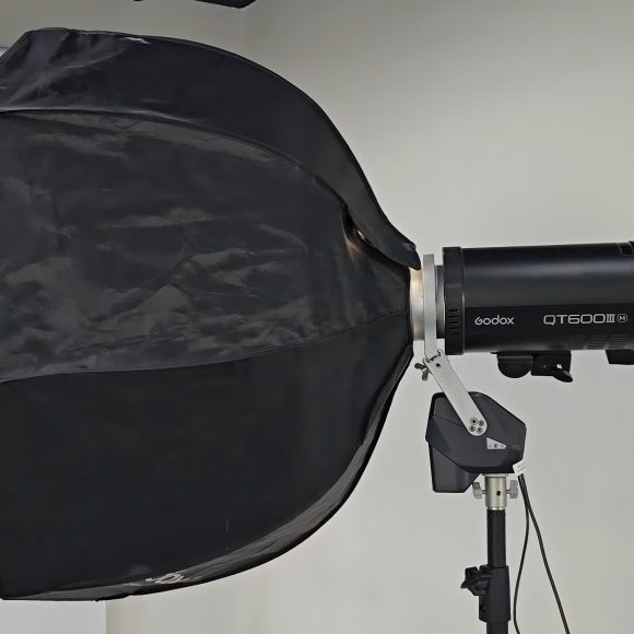 A black Godox QT600II flash with a large octagonal softbox on a light stand in a studio setting.
