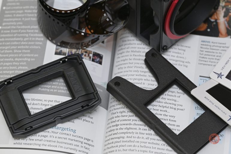 Close-up of camera parts and film negatives on an open book with text and images visible in the background.