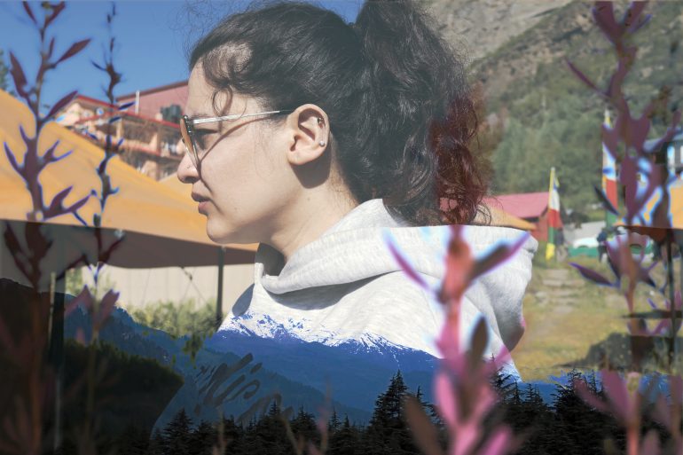 A woman in glasses stands outdoors; mountains and foliage are overlaid in a double exposure effect.