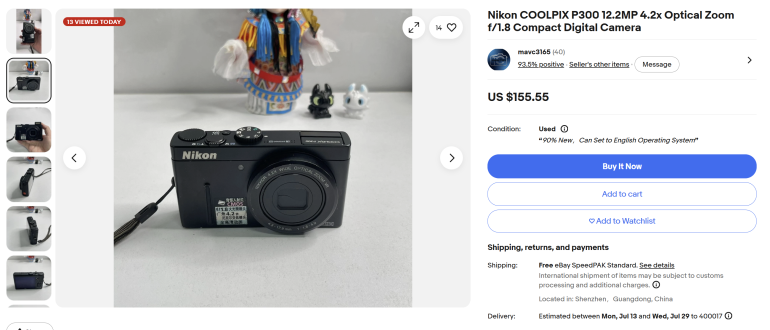Nikon COOLPIX P300 digital camera on a white surface with small figurines in the background.