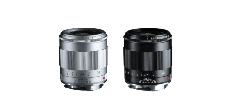 Two camera lenses, one silver and one black, standing upright on a white background.