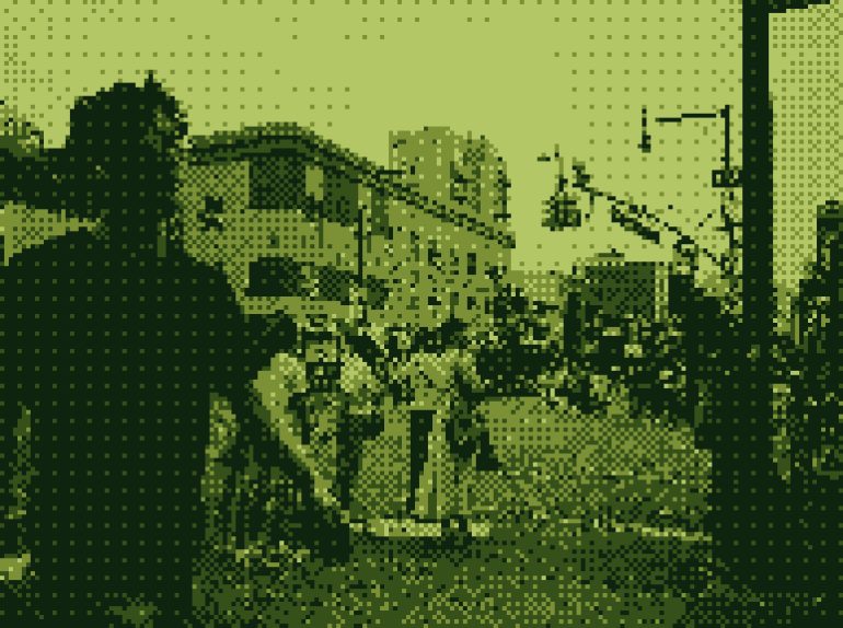 A pixelated street scene with people gathered outdoors, some buildings, and a traffic light visible.
