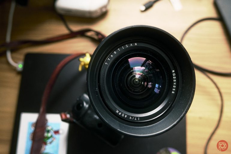 Close-up of a camera lens on a table with reflections visible on the lens glass.
