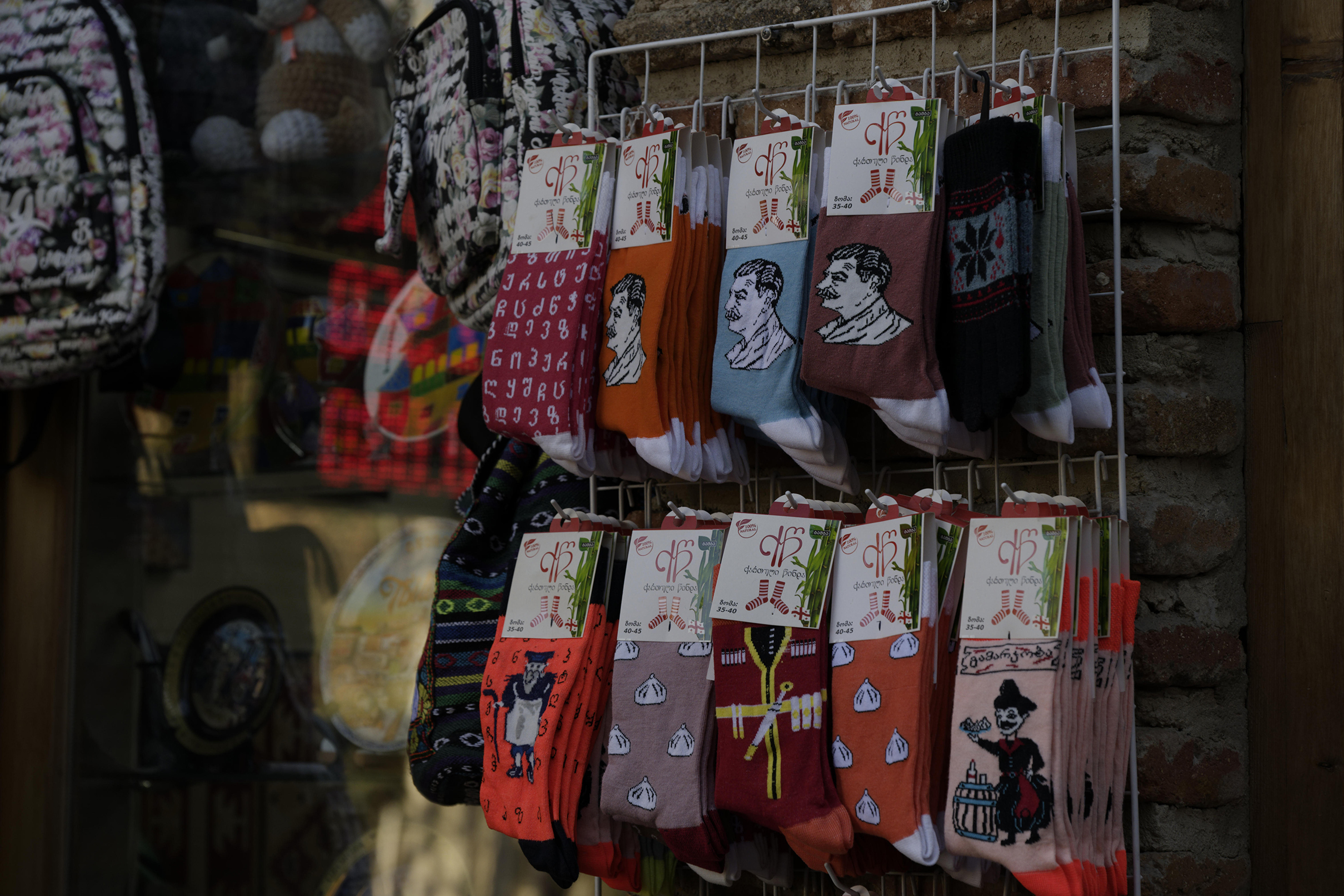 Colorful socks with various unique designs and patterns are displayed for sale on a metal rack.