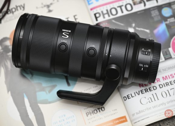Nikon Z 70-200mm f2.8 S VR II Review Update: Awesome For Sports Photography A Nikon NIKKOR S camera lens resting on top of several open photography magazines.