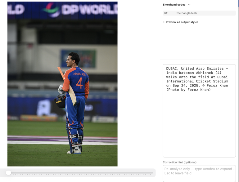 Cricketer in blue and orange gear walks onto a cricket field, holding a bat and helmet, stadium in background.
