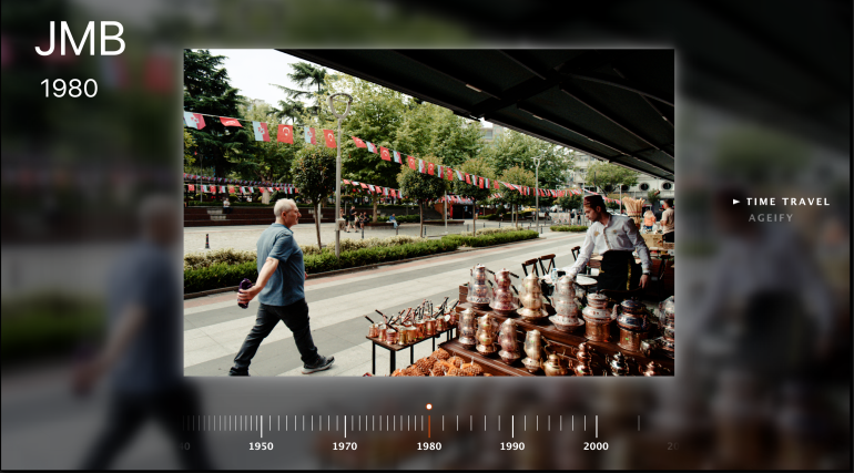A man walks past a street market stall selling copperware, with flags and trees in the background.