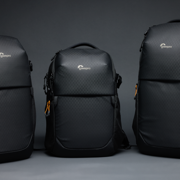 Three black camera backpacks of different sizes are displayed side by side on a dark background.