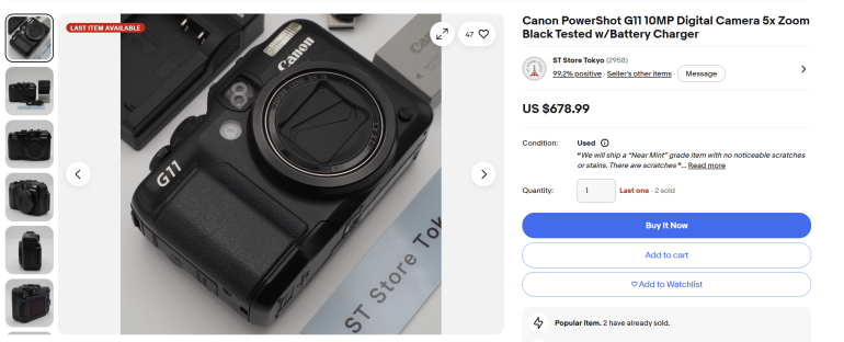 Close-up of a Canon PowerShot G11 digital camera with accessories shown on a light surface.