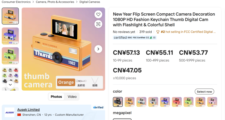 Orange retro-style digital camera keychain with thumb camera text, displayed on an online store page.